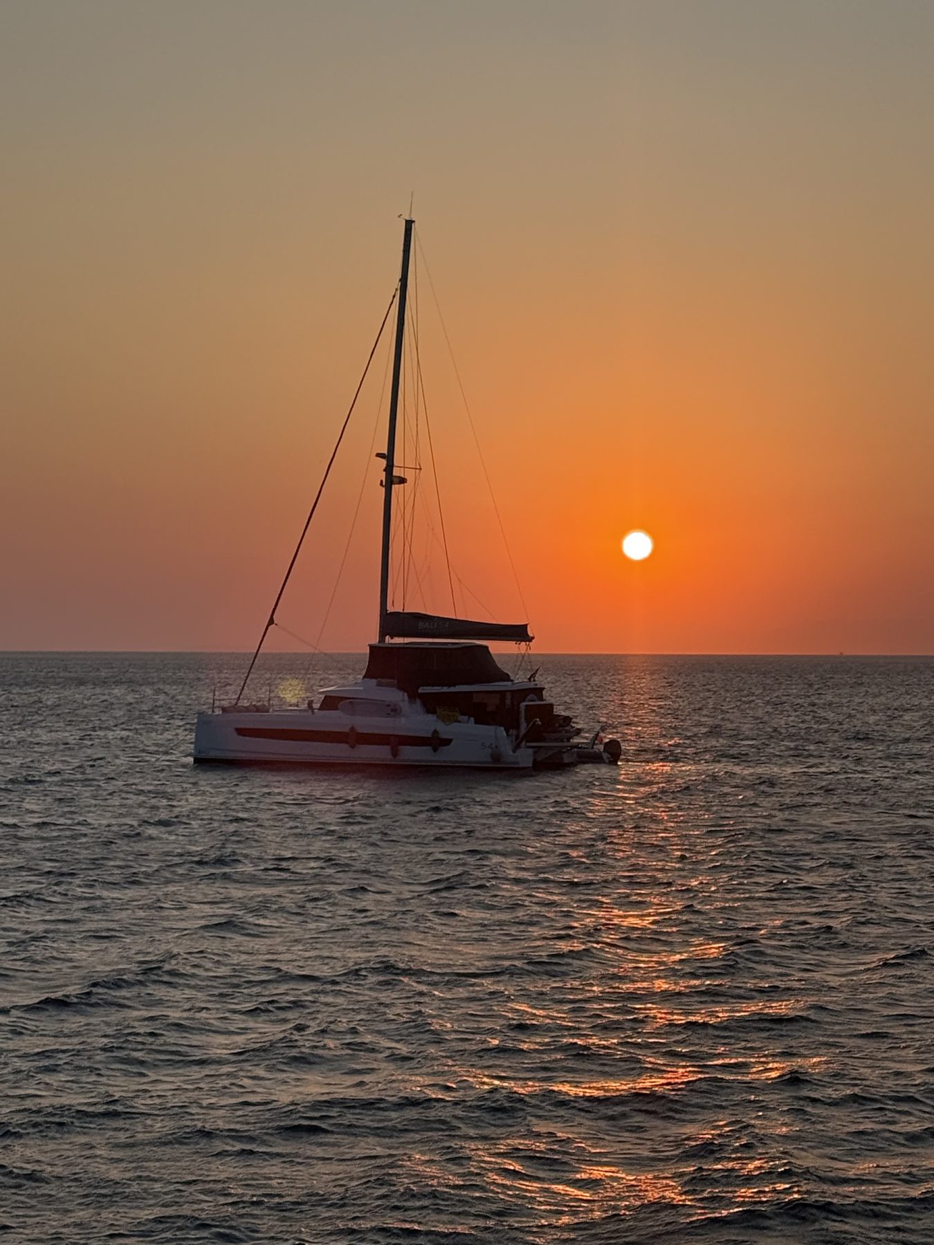 A sailboat silhouetted against the sunset in Greece